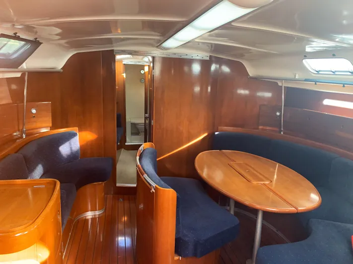 Ayla Yacht Photos Pics Interior of 1991 Beneteau First sailboat with wooden furnishings and blue seating.