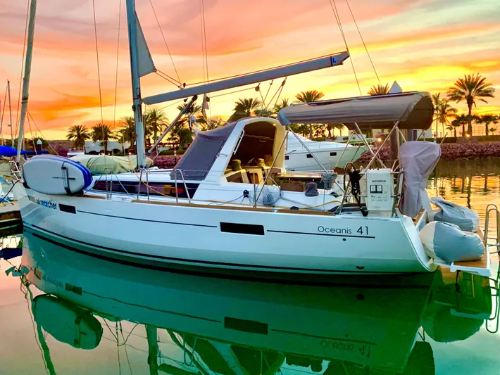 Sol Searcher Yacht Photos Pics 2013 Beneteau Oceanis 41 sailboat docked at sunset with palm trees in the background.