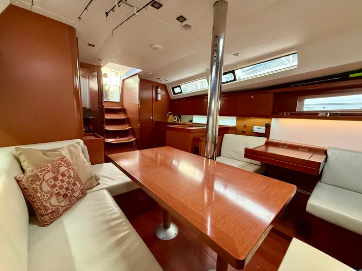 Sol Searcher Yacht Photos Pics Interior of 2013 Beneteau Oceanis 41 sailboat with wooden table and seating area.