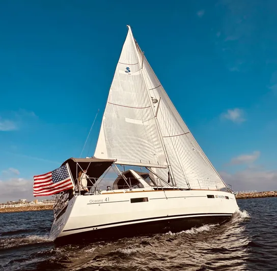 Sol Searcher Yacht Photos Pics 2013 Beneteau Oceanis 41 sailing with American flag on open water.