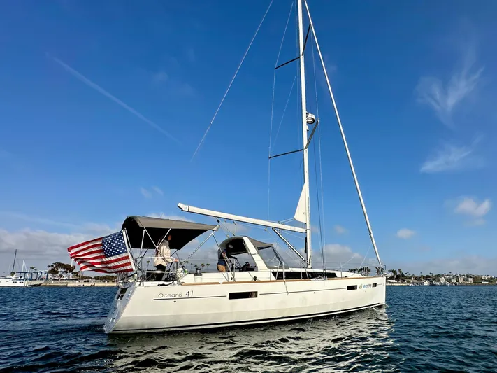 Sol Searcher Yacht Photos Pics 2013 Beneteau Oceanis 41 sailboat on calm water, clear sky, American flag displayed.