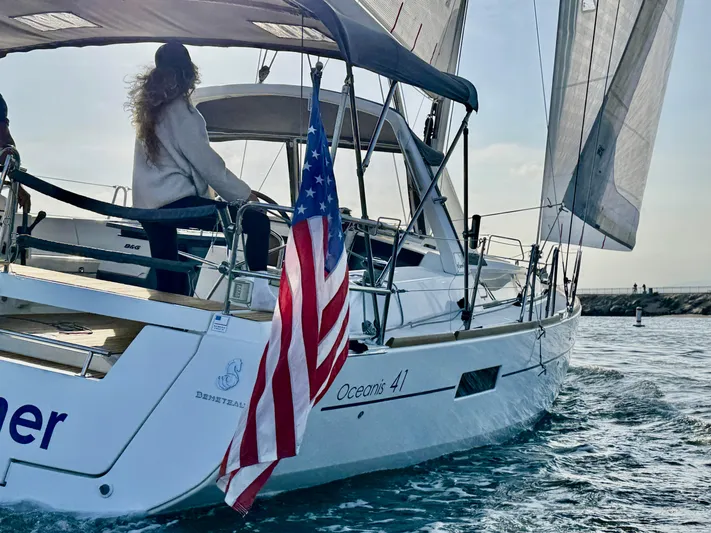 Sol Searcher Yacht Photos Pics 2013 Beneteau Oceanis 41 sailboat with American flag, sailing on open water.