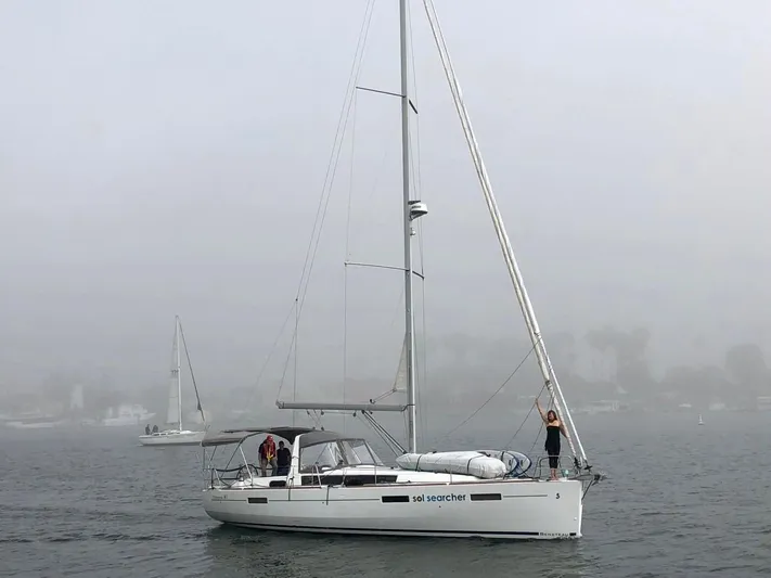 Sol Searcher Yacht Photos Pics 2013 Beneteau Oceanis 41 sailboat on misty water, with people on deck.