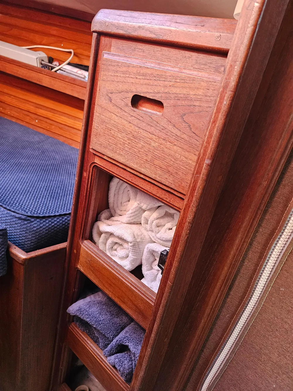 Wooden storage cabinet with towels inside a 1984 Schock NY 36 sailboat interior.