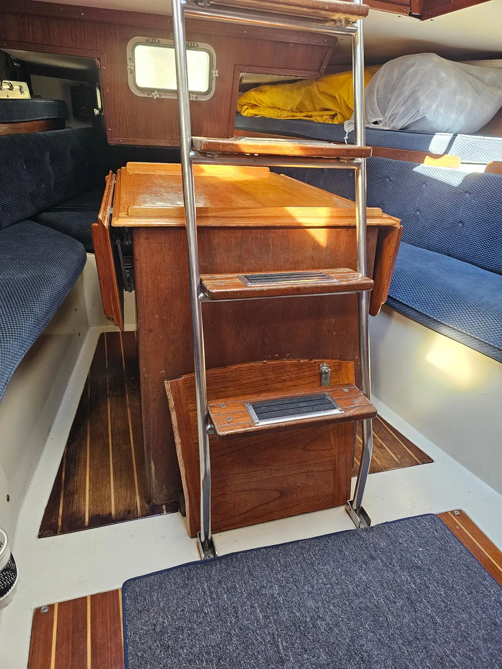 Interior of 1984 Schock NY 36 sailboat with wooden steps and blue seating.