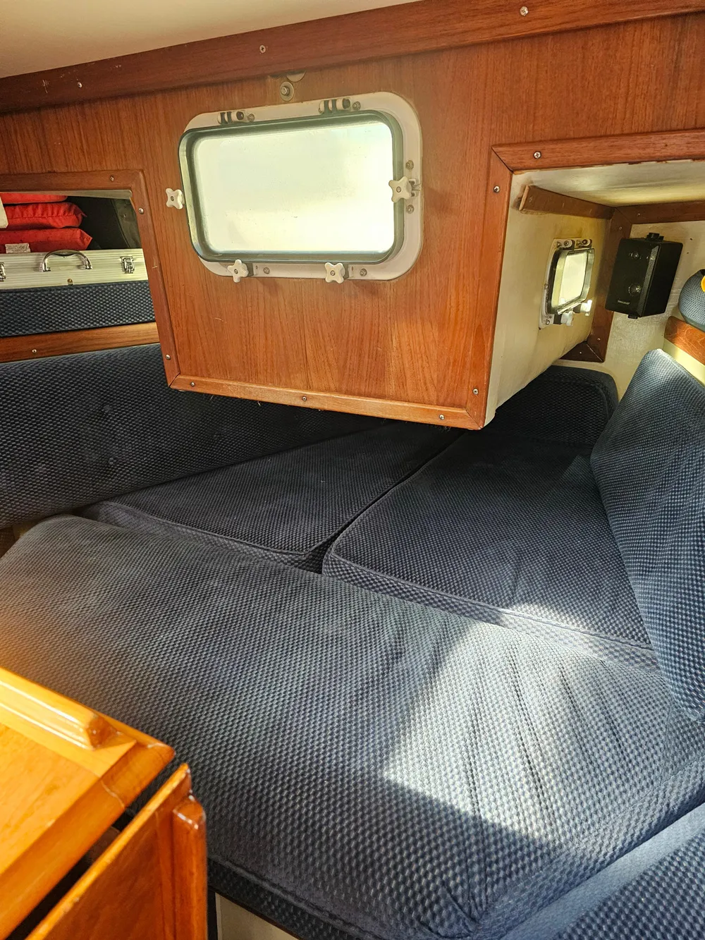 Cozy cabin interior of 1984 Schock NY 36 sailboat with blue cushions and wooden accents.