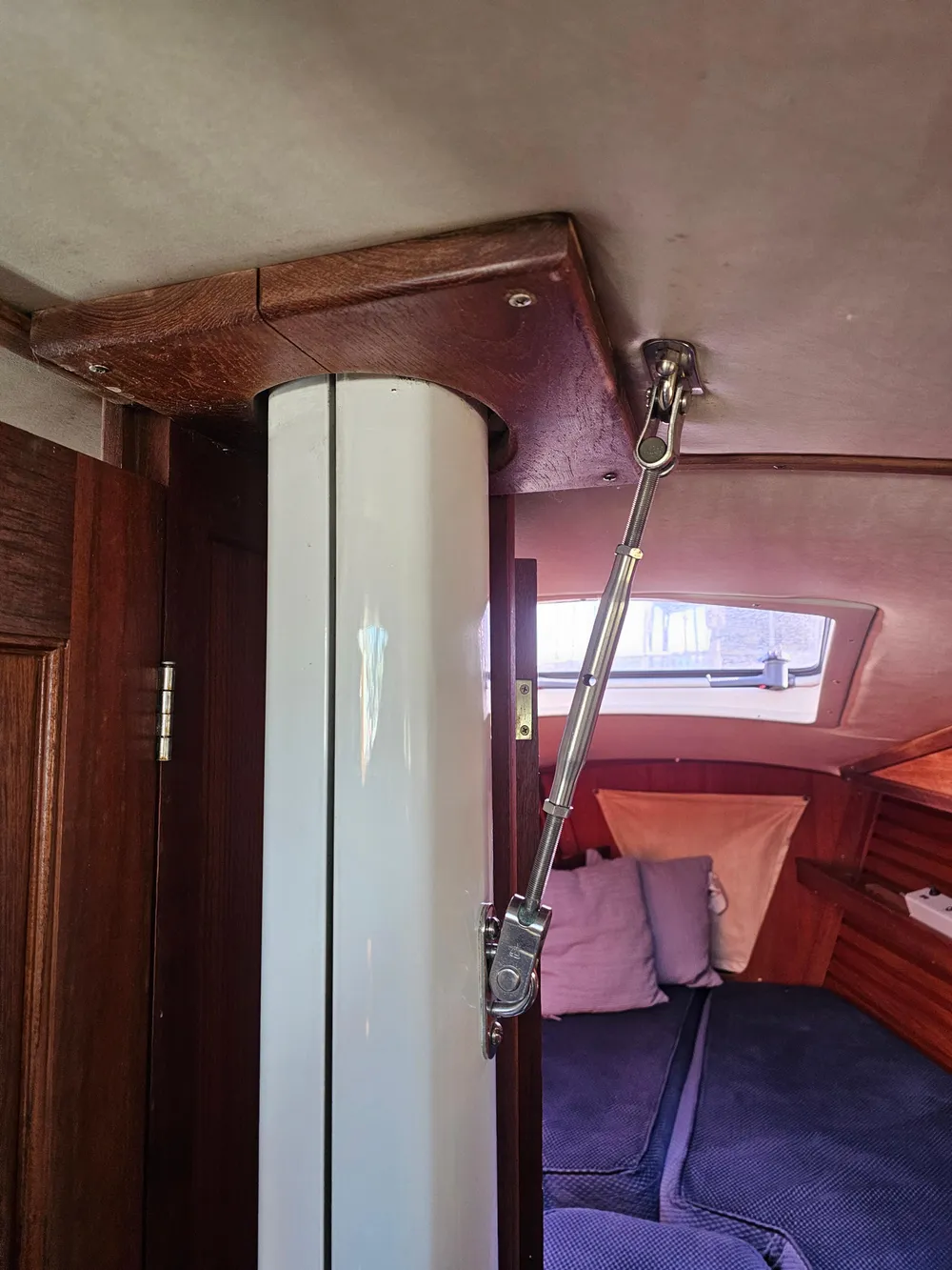 Interior of a 1984 Schock NY 36 sailboat, featuring a mast support and cozy cabin area.