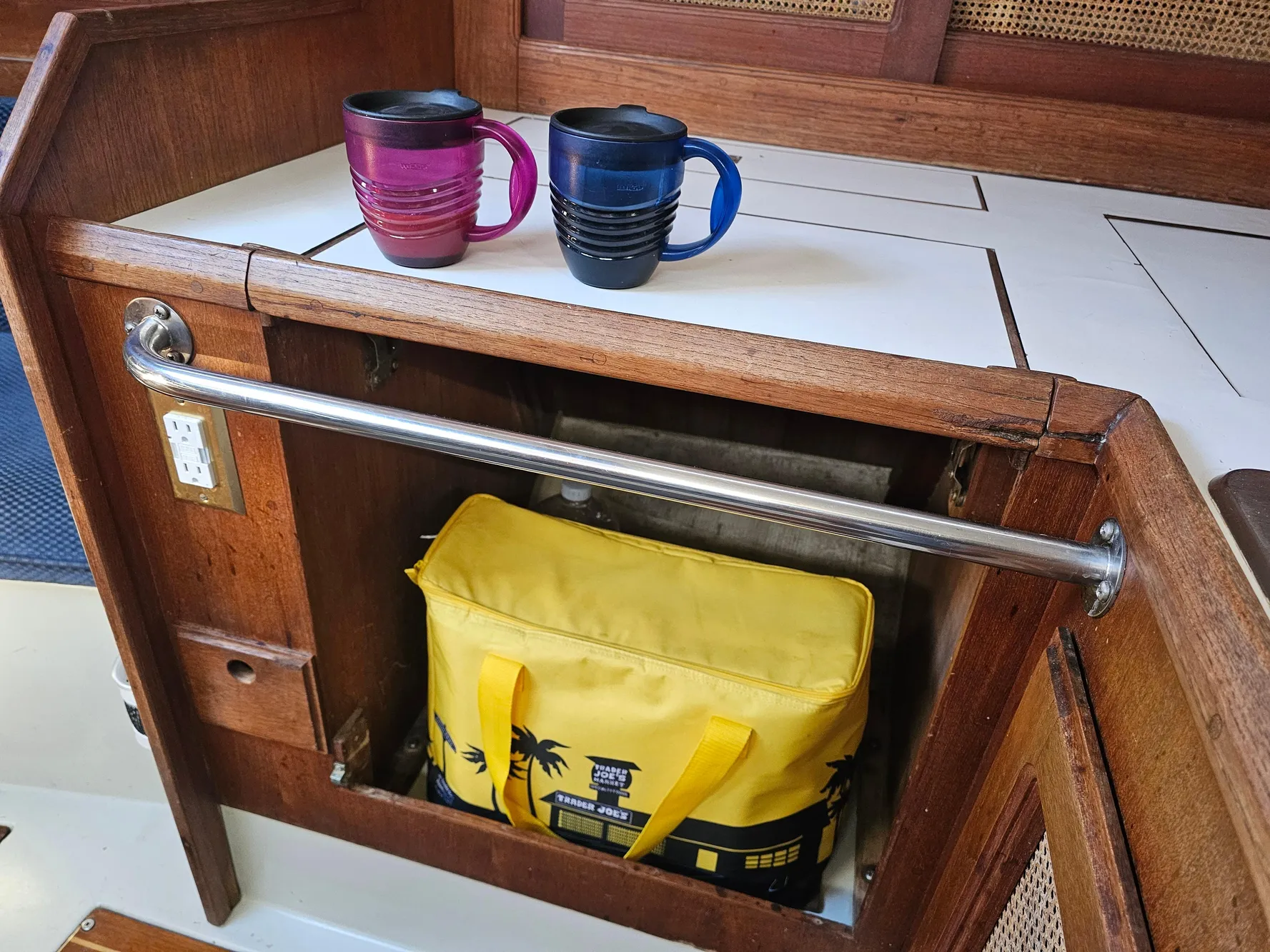 Wooden boat interior with two mugs and a yellow bag, Schock NY 36, 1984.