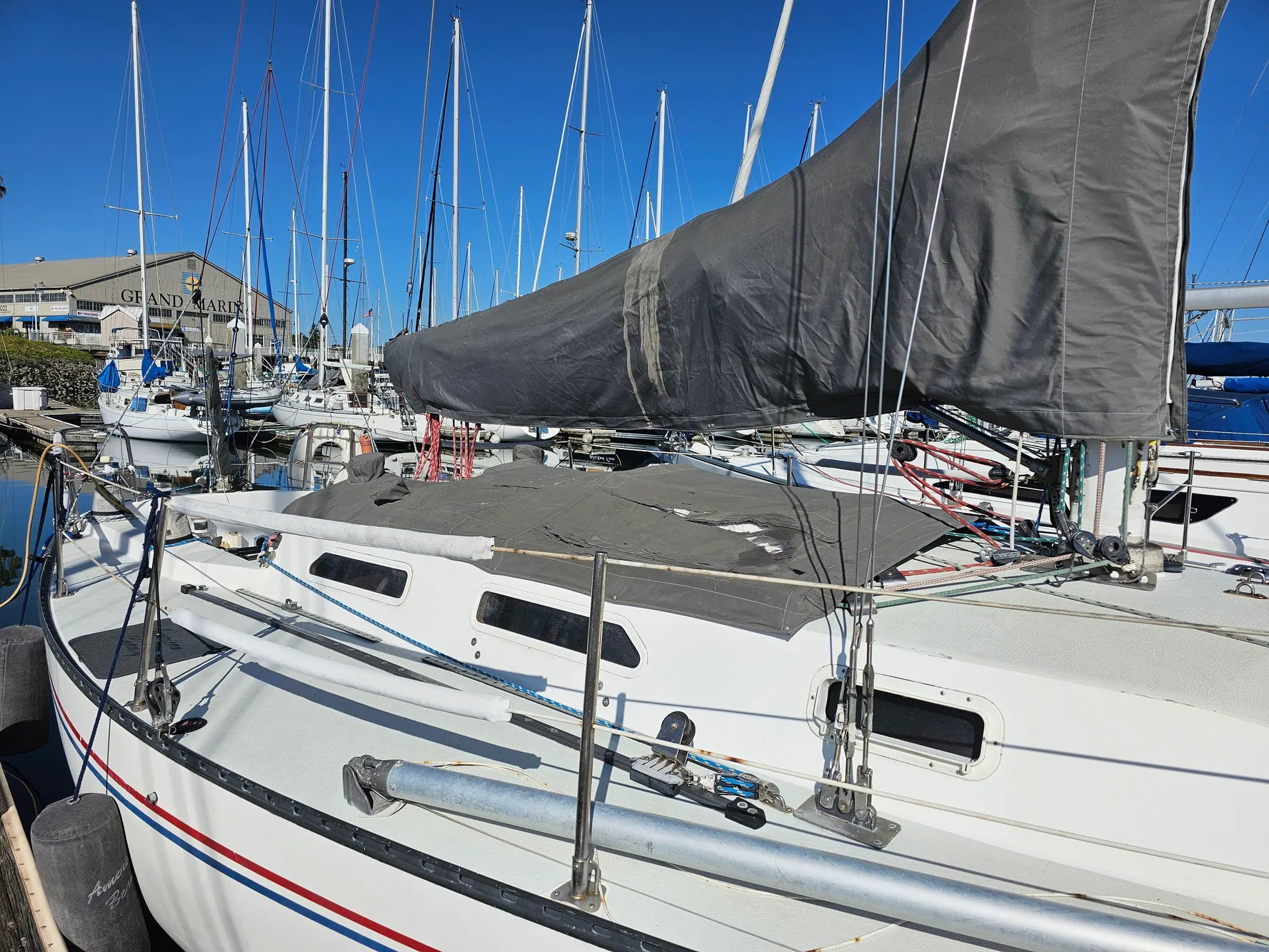 1984 Schock NY 36 sailboat docked at marina, featuring covered sails and clear blue sky.