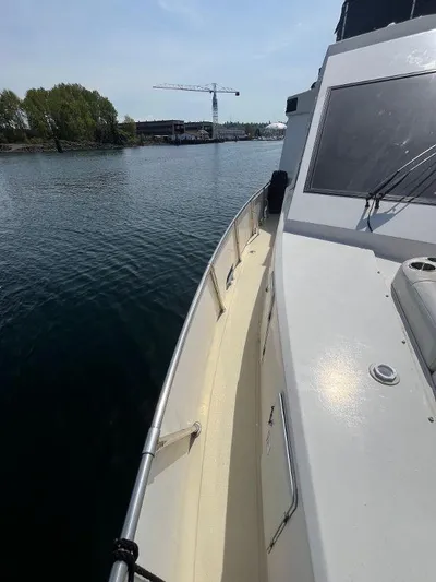 Lady Elaine Yacht Photos Pics 1993 Kha Shing Motoryacht on calm water, with a crane and trees in the background.