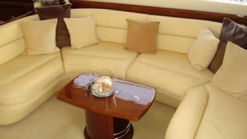  Yacht Photos Pics Luxurious beige seating area on 2004 Princess 65 yacht with wooden table and cushions.