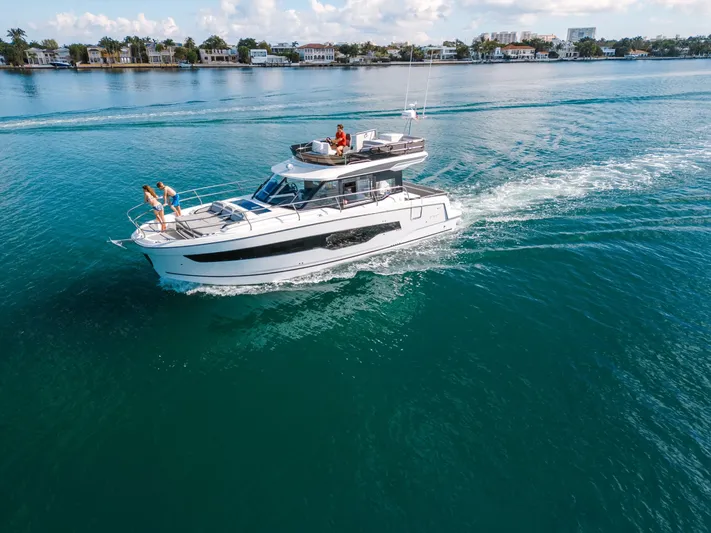  Yacht Photos Pics 2024 Jeanneau NC 1295 Fly cruising on clear blue water with people on deck.