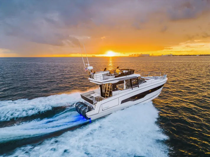  Yacht Photos Pics 2024 Jeanneau NC 1295 Fly yacht cruising at sunset on open water.
