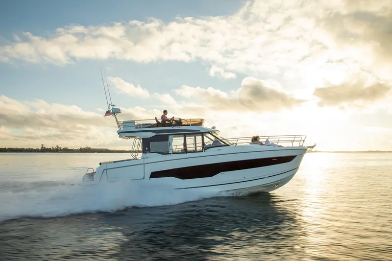  Yacht Photos Pics 2024 Jeanneau NC 1295 Fly cruising on calm water at sunset.
