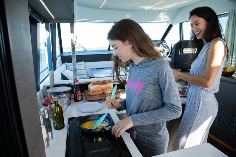  Yacht Photos Pics Mother and daughter cooking in Jeanneau NC 1295 Fly yacht kitchen, 2024 model.