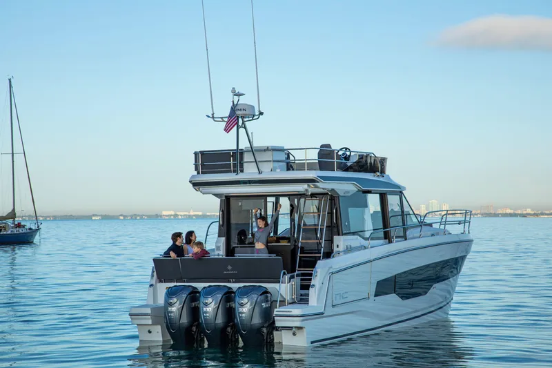  Yacht Photos Pics 2024 Jeanneau NC 1295 Fly yacht cruising on calm waters with passengers onboard.