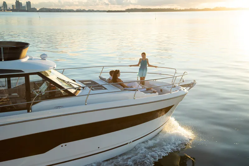  Yacht Photos Pics 2024 Jeanneau NC 1295 Fly yacht cruising on calm waters at sunset.