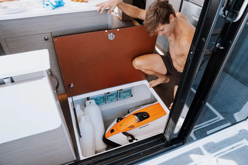  Yacht Photos Pics Man accessing storage compartment on 2024 Jeanneau NC 1295 Fly boat.