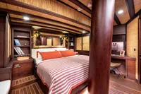 Luxurious cabin interior of 1993 Custom Gulet Motorsailer with wood accents and cozy bedding.