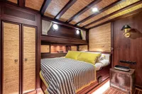 Luxurious cabin interior of 1993 Custom Gulet Motorsailer with wood paneling and cozy bedding.