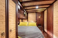 Luxurious cabin interior of 1993 Custom Gulet Motorsailer with wood paneling and cozy bedding.
