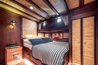 Luxurious cabin interior of 1993 Custom Gulet Motorsailer with wood paneling and cozy bed.