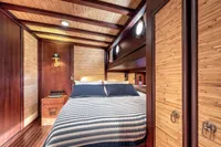 Luxurious cabin interior of 1993 Custom Gulet Motorsailer with wood paneling and cozy bedding.