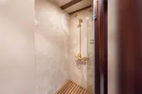 Luxurious shower with marble walls and wooden floor on a 1993 Custom Gulet Motorsailer.