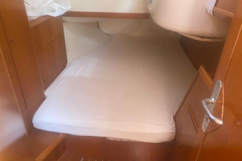  Yacht Photos Pics Cozy cabin interior of 2003 Jeanneau Sun Odyssey 45.2 sailboat with wooden cabinetry.