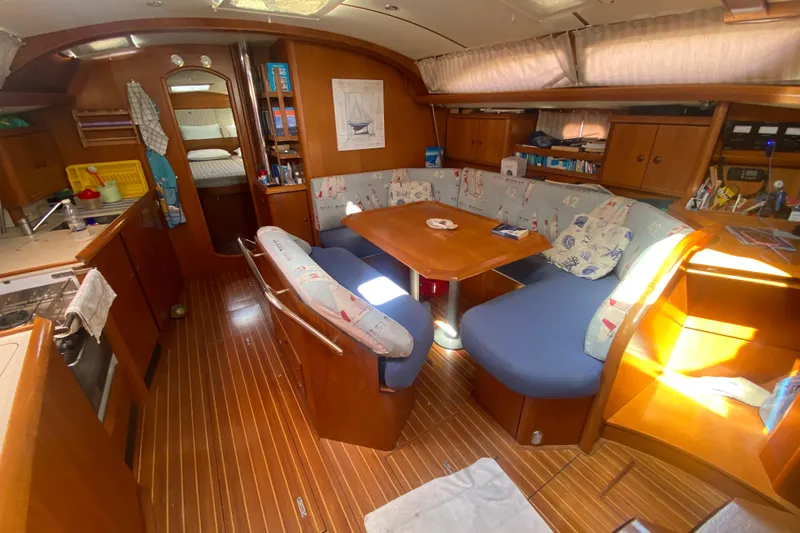  Yacht Photos Pics Interior of 2003 Jeanneau Sun Odyssey 45.2 sailboat with cozy seating and wooden finishes.