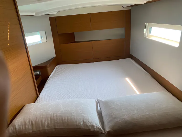 Vanilla IV Yacht Photos Pics Interior cabin of 2023 Jeanneau Sun Odyssey 410 with cozy bed and wooden accents.