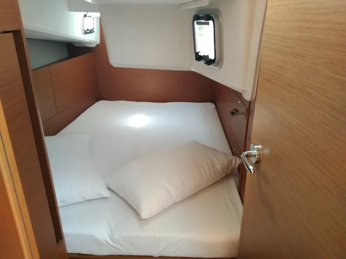 Vanilla IV Yacht Photos Pics 2023 Jeanneau Sun Odyssey 410 cabin with cozy bed and wooden interior.