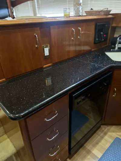  Yacht Photos Pics 2003 Carver 466 Motor Yacht kitchen with sleek black countertop and wooden cabinetry.