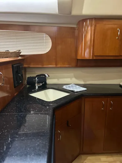  Yacht Photos Pics Luxurious kitchen interior of 2003 Carver 466 Motor Yacht with wooden cabinets and black countertop.