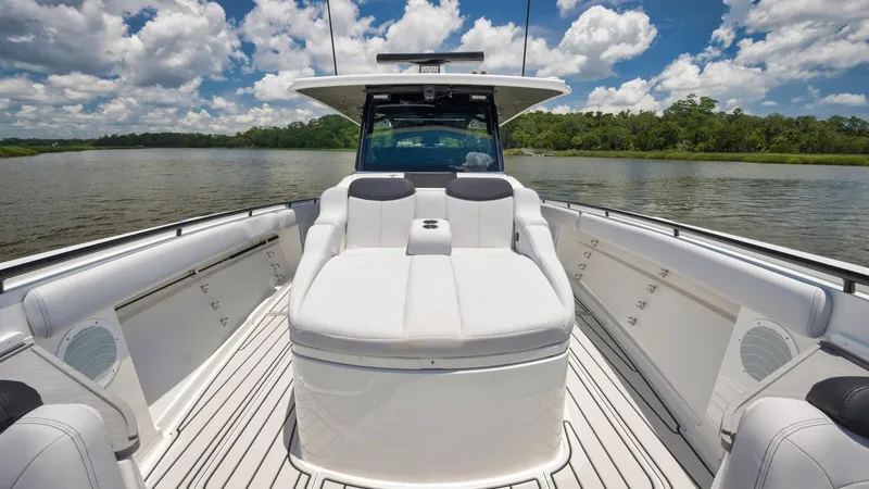Traveller Yacht Photos Pics 2021 HCB Suenos boat interior with white seating, on a calm lake under a blue sky.