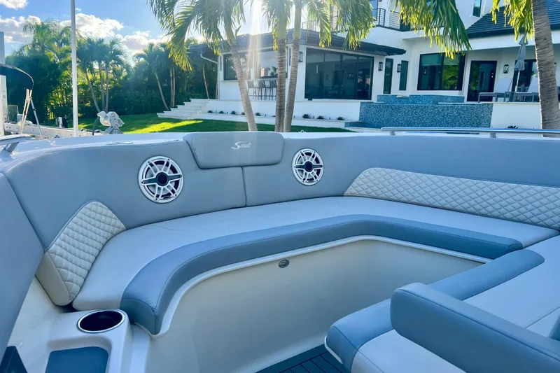  Yacht Photos Pics 2023 Scout 350 LXZ boat interior with luxurious seating and speakers, near a modern house.