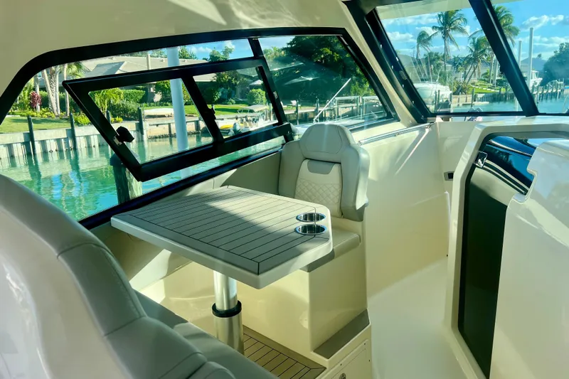  Yacht Photos Pics 2023 Scout 350 LXZ boat interior with seating and table, overlooking a scenic waterfront.