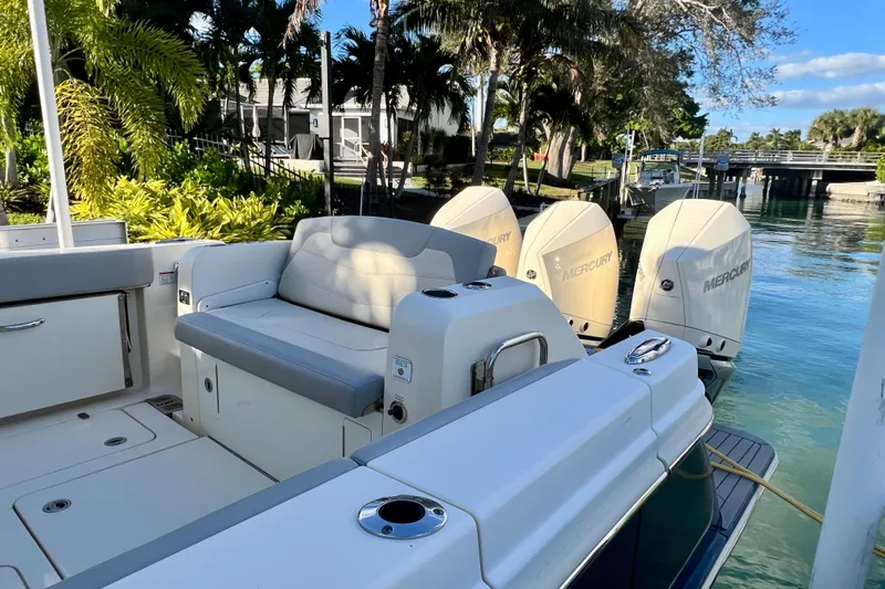  Yacht Photos Pics 2023 Scout 350 LXZ boat with Mercury engines docked by lush greenery.