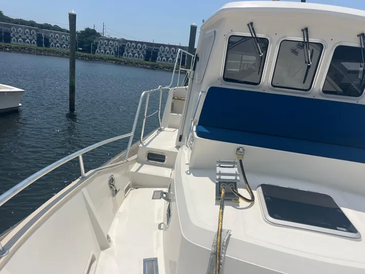  Yacht Photos Pics Cherubini Independence 1998 boat deck with blue seating, docked by waterfront buildings.