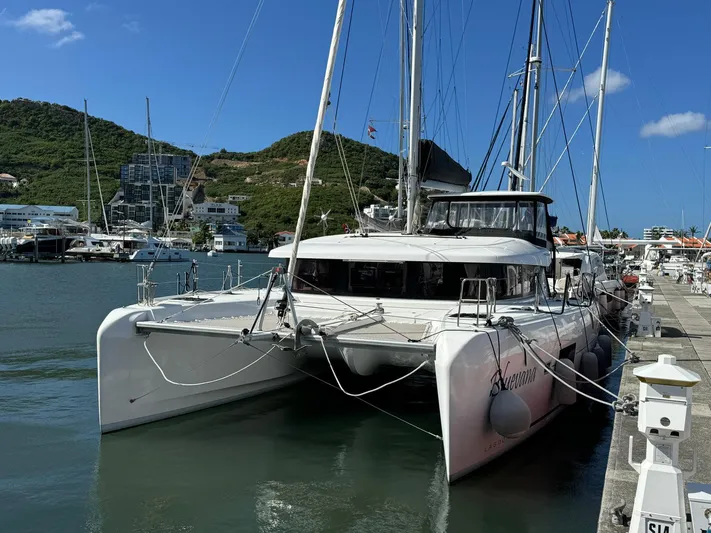 Bluevana Yacht Photos Pics 2023 Lagoon 42 catamaran docked in a marina, surrounded by hills and clear skies.