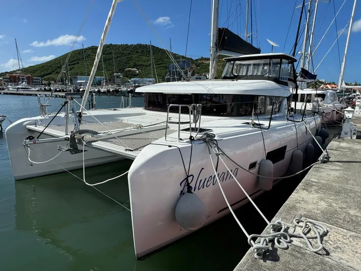 Bluevana Yacht Photos Pics 2023 Lagoon 42 catamaran docked in marina, clear sky, scenic background.
