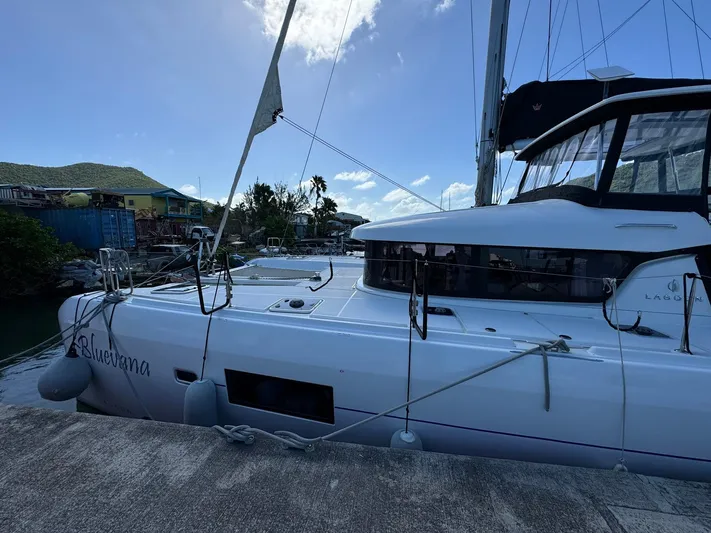 Bluevana Yacht Photos Pics 2023 Lagoon 42 catamaran docked at a marina under a clear blue sky.