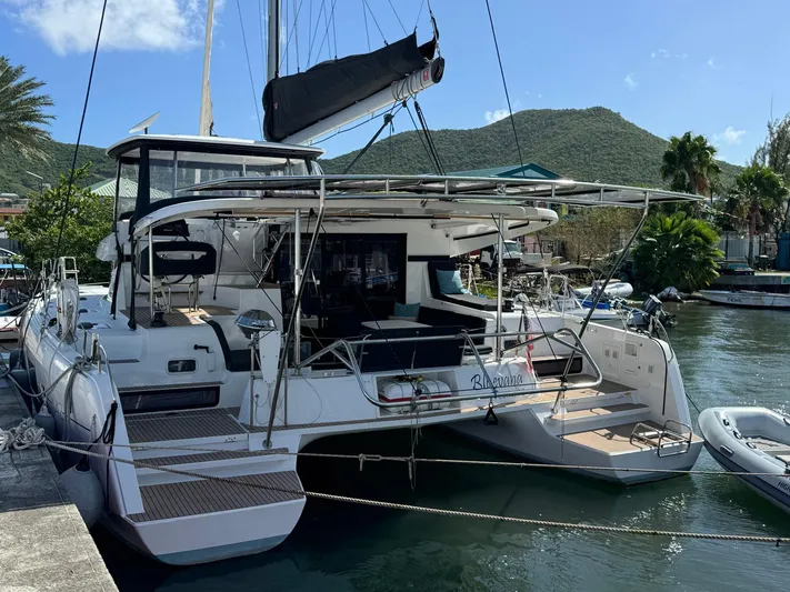 Bluevana Yacht Photos Pics 2023 Lagoon 42 catamaran docked in a scenic marina with lush hills.