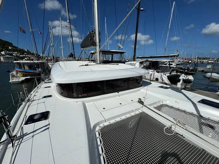 Bluevana Yacht Photos Pics 2023 Lagoon 42 catamaran docked in a marina under a clear blue sky.