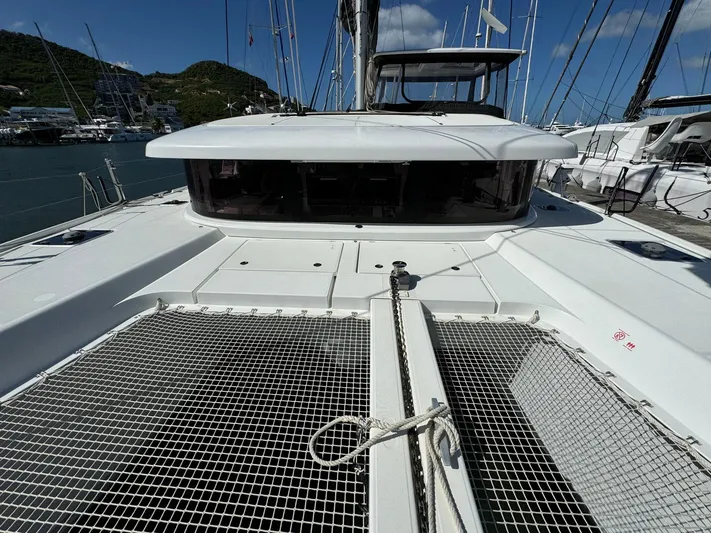 Bluevana Yacht Photos Pics 2023 Lagoon 42 catamaran deck with netting, docked in a marina.