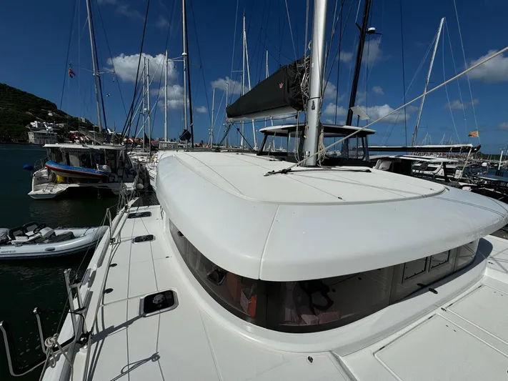 Bluevana Yacht Photos Pics 2023 Lagoon 42 catamaran docked in a marina under a clear blue sky.