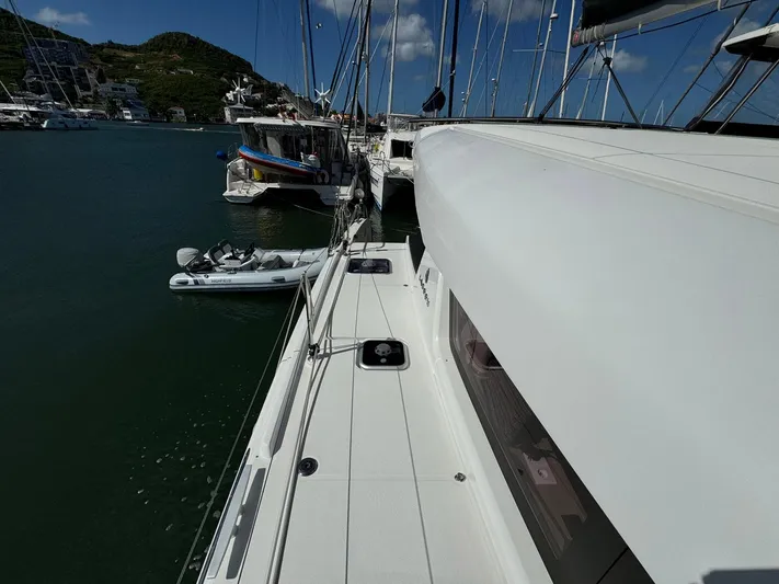 Bluevana Yacht Photos Pics 2023 Lagoon 42 catamaran docked in a marina, with clear skies and surrounding boats.