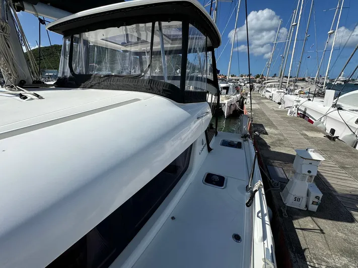 Bluevana Yacht Photos Pics 2023 Lagoon 42 catamaran docked at a marina under a clear blue sky.