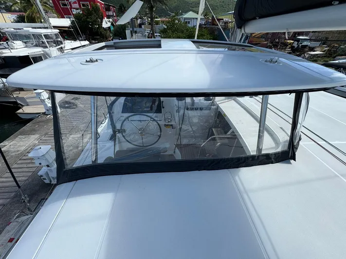 Bluevana Yacht Photos Pics 2023 Lagoon 42 catamaran helm station with protective canopy, docked at a marina.