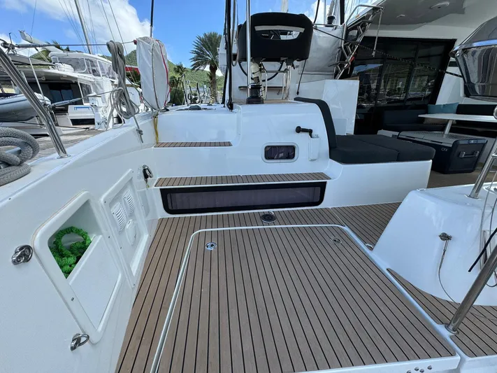 Bluevana Yacht Photos Pics 2023 Lagoon 42 yacht deck with seating, wood flooring, and marina view.